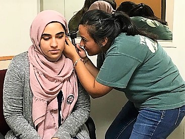 A woman checks the ear of another woman