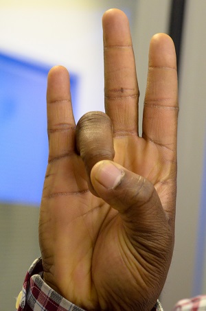 A hand gesture with the thumb touching the ring finger representing a 'cougar paw'