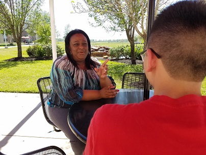 A Black woman sitting at an outdoor table with a male student