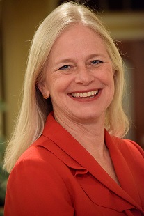 Portrait of a blond woman wearing a red suit smiling