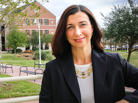 Portrait of a hispanic woman with brown hair wearing dark business jacket.