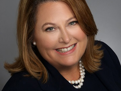 Portrait of a woman with light brown hair smiling in a business jacket