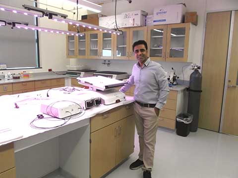 Picture of a professor smiling next to donated equipment.