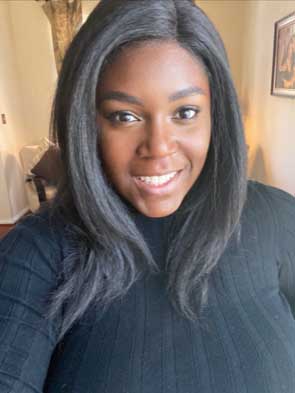 Portrait of a Black woman smiling wearing a black top.