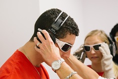 A nursing student wearing special glasses is outfitted with white-noise headphones