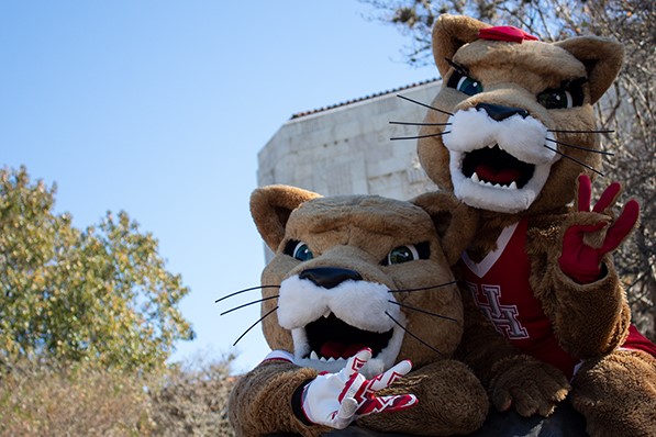 UH mascots Shasta and Sasha sitting on the cougar statue.